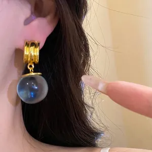Eleganti orecchini vintage a sfera in resina con finitura dorata indossati all'orecchio
