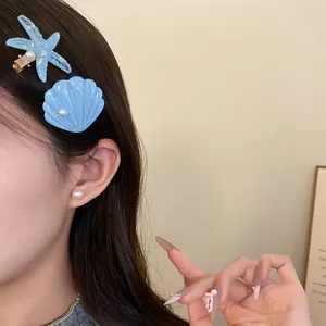 Close-up view of blue resin starfish and shell hair clips worn on long dark hair with pearls.