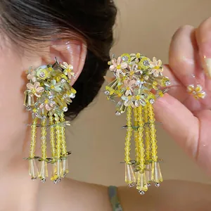 Close-up of elegant forest style glass tassel earrings with yellow sequin flowers