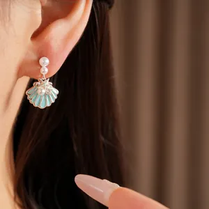 Primo piano dettagliato di orecchini a conchiglia in smalto blu con perle e zirconi