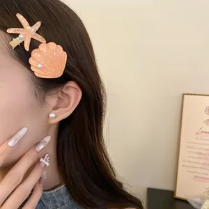 Detailed view of stylish orange resin starfish and shell hair clips worn on brown hair