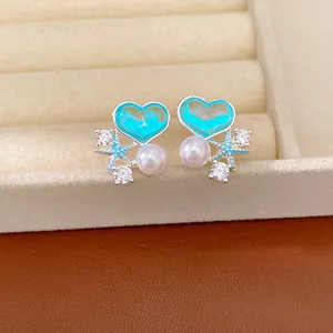 Primo piano di eleganti orecchini a cuore in smalto blu con perle e ciondoli a stella.