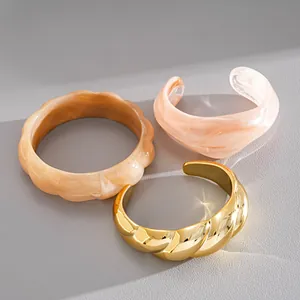 Vista dettagliata di bracciali in acrilico marmorizzato e bracciale rigido dorato chic