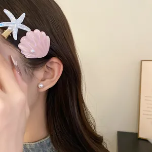 Close-up detail of resin starfish and pink shell hair clips set on a model's hair.