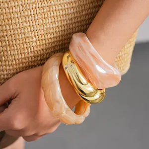 Primo piano di bracciali in acrilico marmorizzato e un bracciale dorato a spirale.
