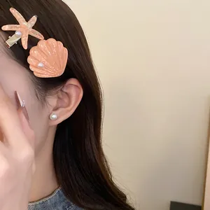 Close-up of shell and starfish hair clips with pearls worn on hair for a seaside look.