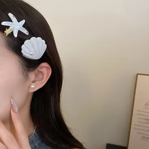 Detailed view of white resin starfish and seashell hair clips worn on elegant dark hair