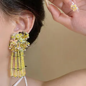 Close-up detail of yellow sequin flower earrings with elegant glass bead tassels