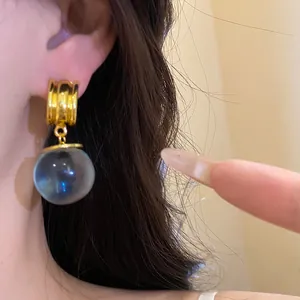 Dettaglio dell'orecchino vintage a sfera in resina con design a cerchio dorato minimalista