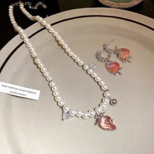 Elegant pearl necklace and earring set with pink translucent strawberry pendants.