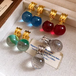 Primo piano di orecchini vintage con pendenti a sfera in resina colorata e cerchi dorati