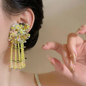 Close-up of elegant forest-style floral tassel earrings with yellow glass beads and sequins