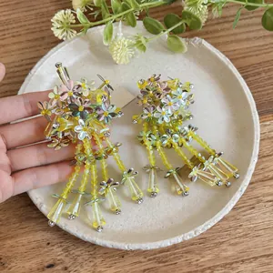 Macro view showing the intricate yellow sequin flowers and glass tassel beads on the earrings