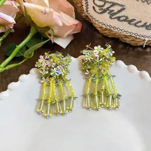 Detailed view of forest-style floral earrings with yellow sequins and glass tassels