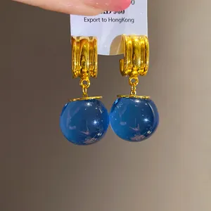 Primo piano di cerchi dorati vintage con sfere di resina blu e perni in argento.