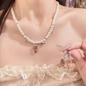 Exquisite detail shot of a pearl necklace and earrings with pink strawberry pendants.