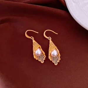 Exquisite hollow gold lace drop earrings with tear drop pearls on luxury brown background