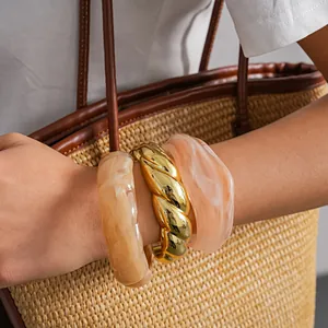 Elegante set di bracciali rigidi in acrilico marmorizzato e oro intrecciato con borsa in paglia