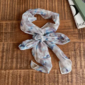 Detailansicht eines süßen Blumen-Netzschals, der auf einem Holztisch gebunden ist.