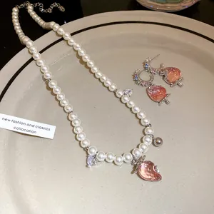 Exquisite pearl necklace and earring set featuring sweet pink strawberry charms on a plate