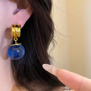 Primo piano di orecchini vintage a sfera in resina blu con finitura oro