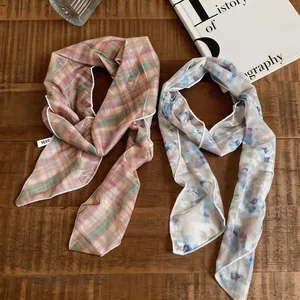 Detailansicht von zwei eleganten Netzschals mit Karo- und Blumenmuster auf Holz für Damen