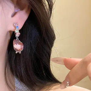 Close-up view of sweet strawberry drop earring featuring sparkling stones on a model's ear