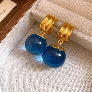 Primo piano di orecchini vintage con pendenti in resina blu e cerchi metallici dorati.