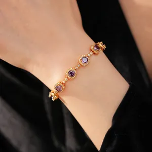 Vintage gold plated zircon bracelet with purple round and square stones on wrist.
