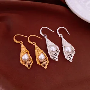 Detailed macro view of elegant hollow lace pearl drop earrings in gold and silver finishes