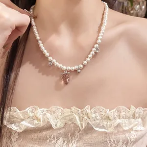 Close-up detail of a sweet pearl necklace featuring a pink glass strawberry pendant.