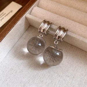 Dettaglio ravvicinato di orecchini vintage con pendente a sfera in resina e finitura argento.