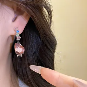Close-up detail of a sweet strawberry pendant earring with colorful crystals on ear