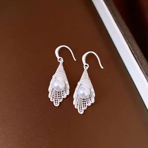 Detailed view of silver lace hollow earrings with drop pearls and elegant hooks.