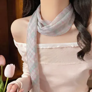 Detail eines karierten Netz-Schals in Pastellrosa und Grün, als modische Krawatte getragen