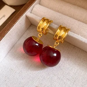 Dettaglio di orecchini vintage in resina con pendenti rotondi e cerchi dorati in scatola