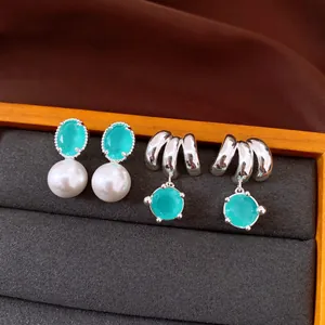 Vista dettagliata di eleganti orecchini in argento con zircone verde e accenti di perle bianche