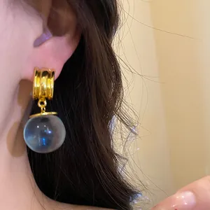 Dettaglio di un orecchino vintage con sfera in resina blu e perno color oro