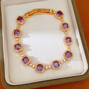 Elegant gold-plated bracelet with purple zircons and white crystals in a luxury box.