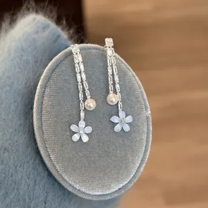 Eleganti orecchini a fiore blu con perle su espositore in morbido velluto azzurro