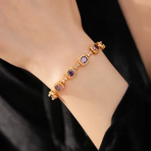 Macro view of vintage gold-plated bracelet with purple cubic zirconia and clear pavé stones.