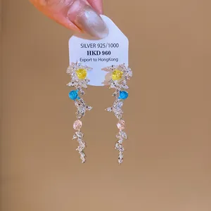 Gros plan de boucles d'oreilles pendantes avec pierres de zircone colorées