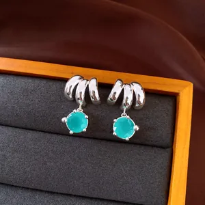 Dettaglio di orecchini a cerchio in argento con eleganti pietre turchesi rotonde