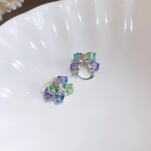 Gros plan de boucles d'oreilles géométriques avec des cristaux cubiques multicolores.