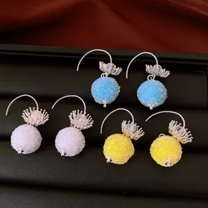 Detail view of three pairs of textured spherical earrings in blue, white, and yellow