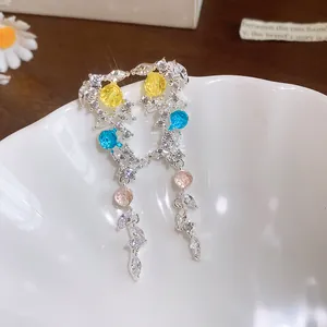 Vue détaillée de boucles d'oreilles pendantes avec zircons colorés et détails de feuilles