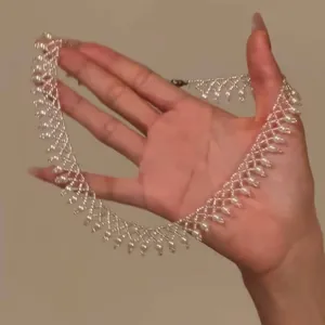 Detailed view of elegant French vintage pearl beaded lace necklace held in hand
