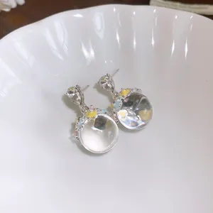 Gros plan de boucles d'oreilles sphériques avec fleurs pastel dans un bol en céramique