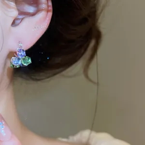 Gros plan de boucles d'oreilles géométriques en zircon avec des pierres violettes et vertes