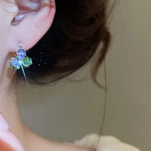 Gros plan détaillé de boucles d'oreilles en zircon géométrique avec cristaux violets et verts
